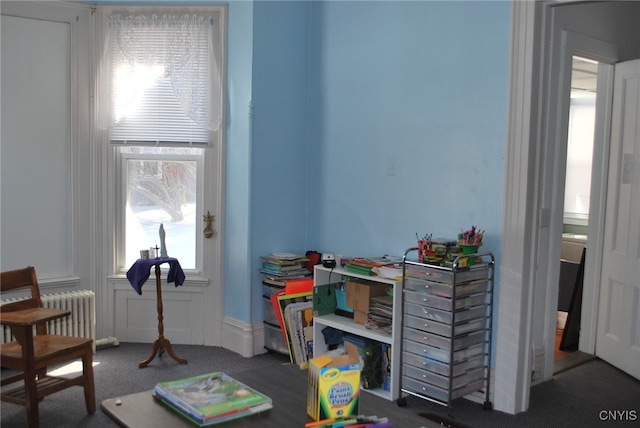 playroom featuring dark colored carpet and radiator