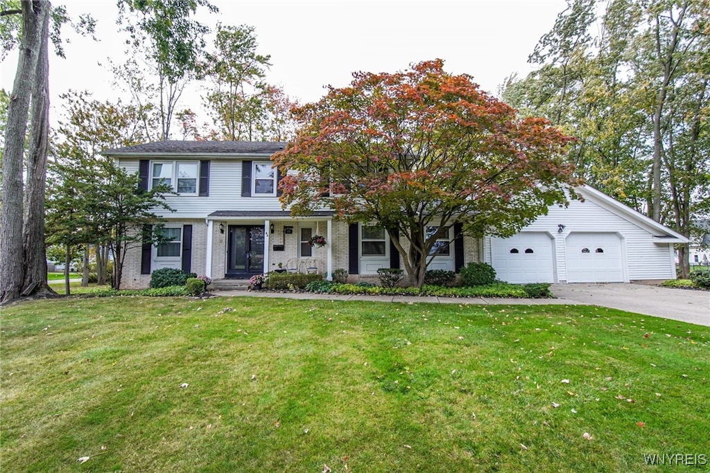 colonial home with a front lawn, covered porch, and a garage