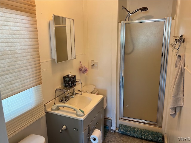 bathroom featuring tile patterned flooring, a shower with door, vanity, and toilet