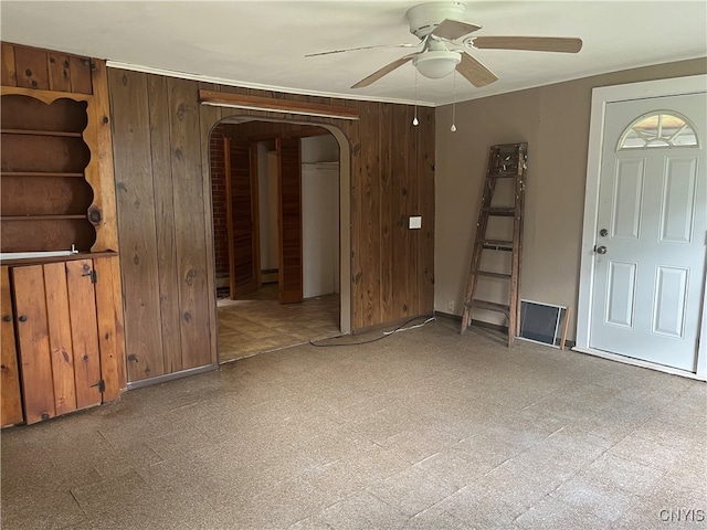 interior space with ceiling fan and wood walls