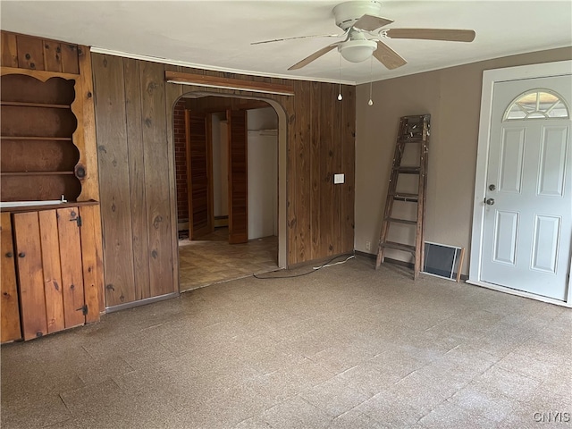 empty room featuring wooden walls and ceiling fan