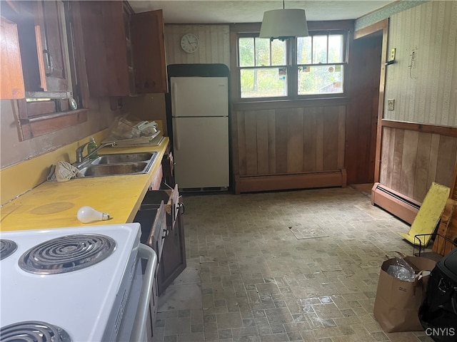 kitchen with wooden walls, baseboard heating, sink, and white appliances