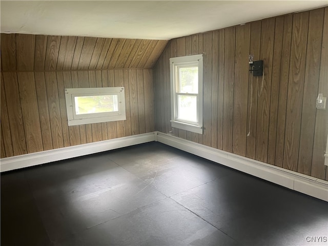 additional living space featuring lofted ceiling and wood walls