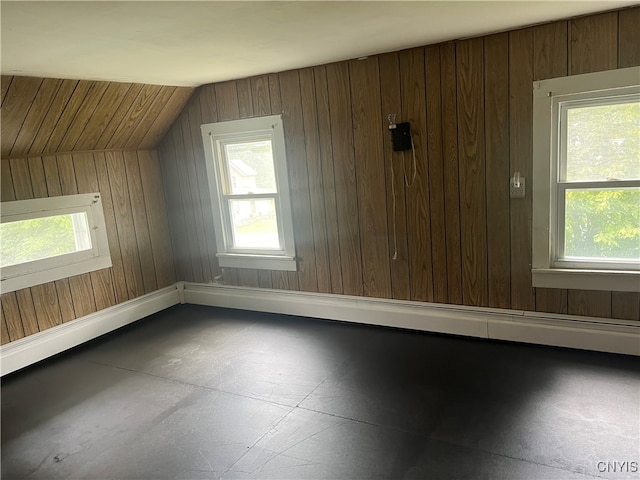 additional living space with lofted ceiling, wood walls, and a healthy amount of sunlight