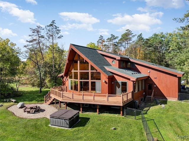 back of house with a fire pit, a deck, and a lawn