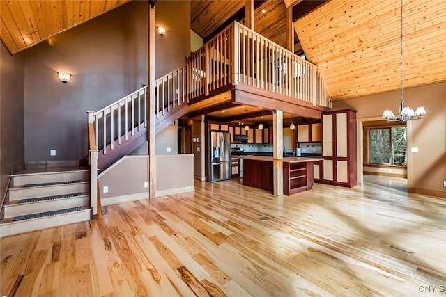 unfurnished living room with light hardwood / wood-style floors, wood ceiling, high vaulted ceiling, and a chandelier