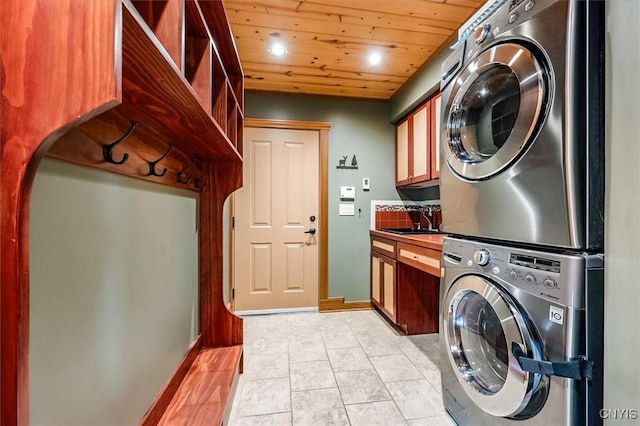 laundry area featuring sink, wooden ceiling, cabinets, light tile patterned floors, and stacked washer and clothes dryer