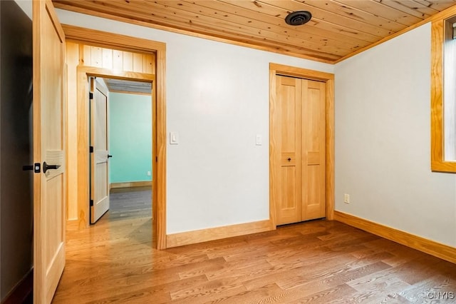 unfurnished bedroom with a closet, crown molding, hardwood / wood-style floors, and wood ceiling