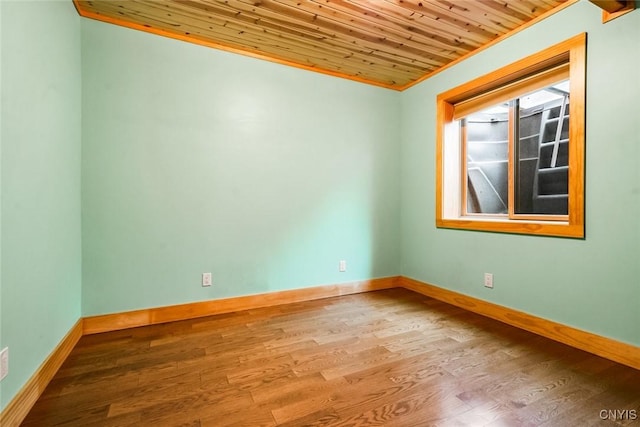 empty room featuring hardwood / wood-style flooring, wooden ceiling, and crown molding