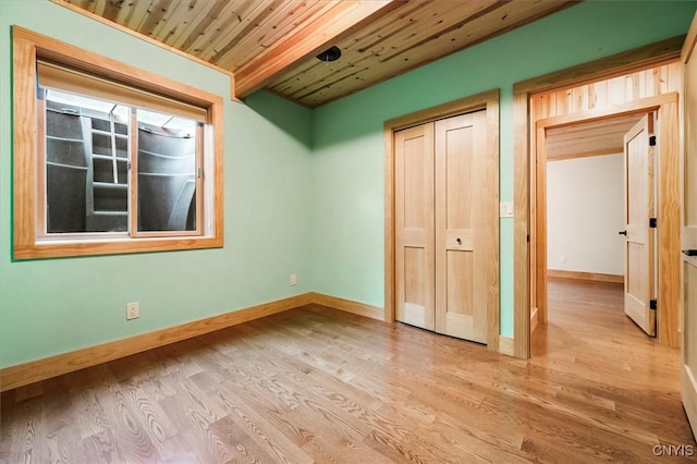 unfurnished bedroom with light hardwood / wood-style floors, wood ceiling, and a closet