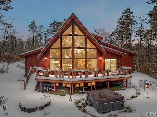 snow covered rear of property featuring a hot tub and a deck