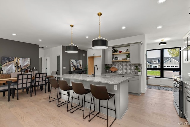 kitchen featuring hanging light fixtures, gray cabinets, and a kitchen island with sink