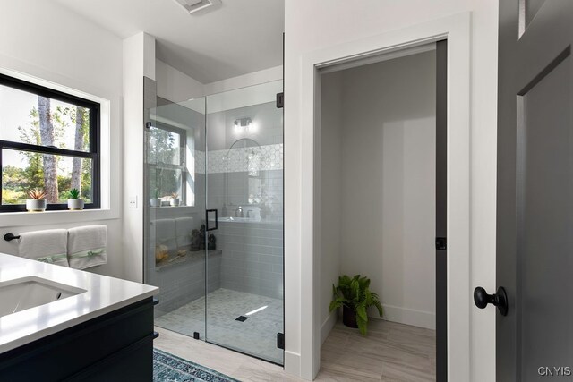 bathroom with a shower with shower door and vanity