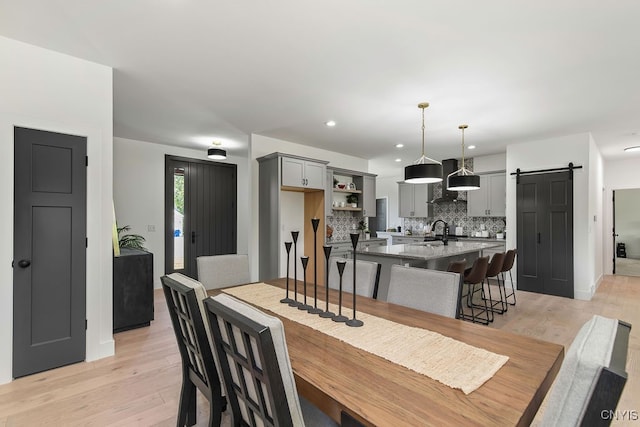 dining area with sink, light hardwood / wood-style floors, and a barn door