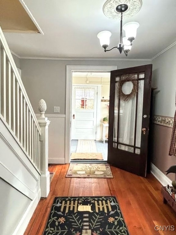 entrance foyer featuring ornamental molding, an inviting chandelier, and hardwood / wood-style floors