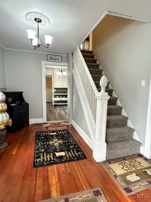 stairs with an inviting chandelier and hardwood / wood-style flooring