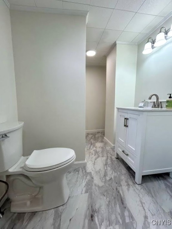 bathroom with a paneled ceiling, vanity, and toilet