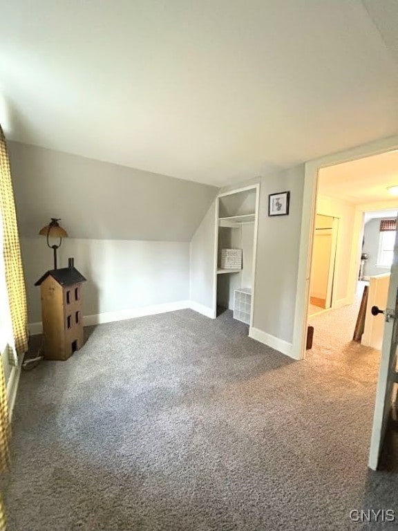 bonus room with vaulted ceiling and carpet flooring