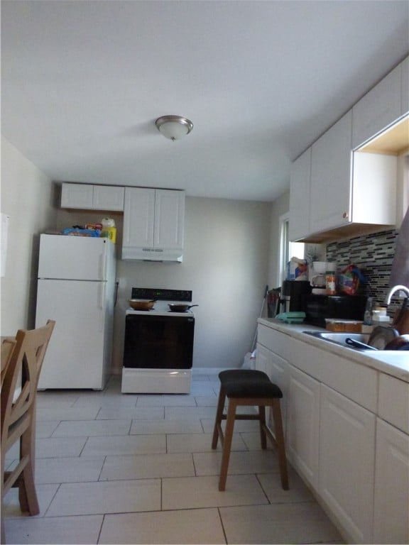 kitchen with white appliances, sink, decorative backsplash, light tile patterned floors, and white cabinetry