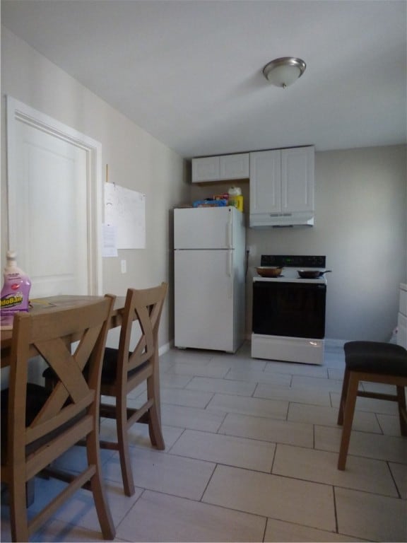 kitchen with white cabinets, light tile patterned flooring, and white appliances