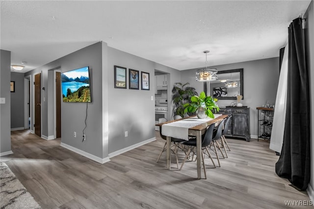 dining area with light hardwood / wood-style floors and a textured ceiling