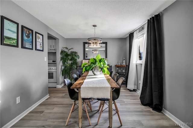 dining space featuring wood-type flooring, a textured ceiling, and a notable chandelier