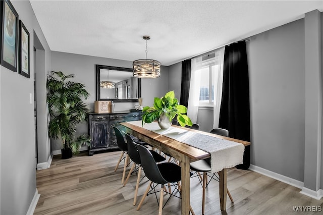 dining space featuring a textured ceiling, a notable chandelier, and light hardwood / wood-style flooring