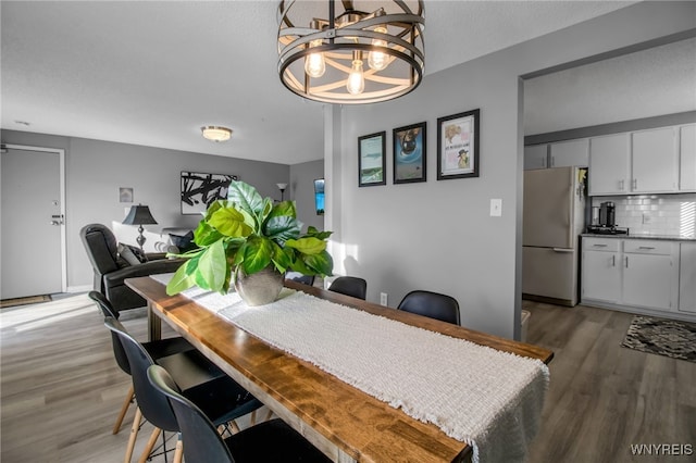 dining space with wood-type flooring and an inviting chandelier