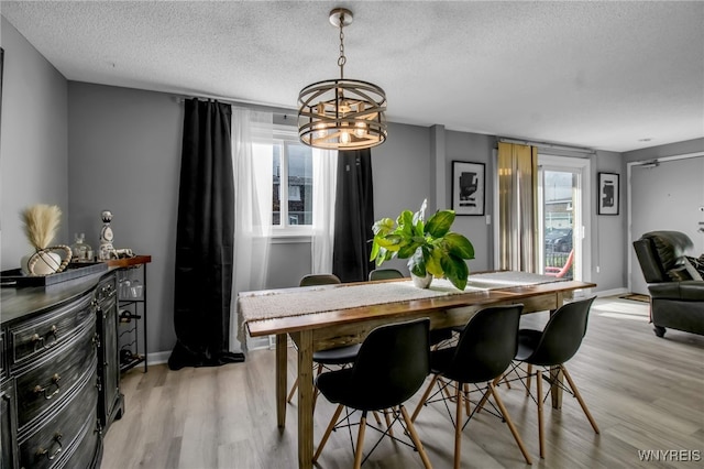 dining space featuring light hardwood / wood-style floors, a notable chandelier, and a textured ceiling