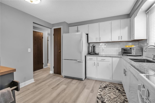 kitchen with white appliances, sink, light hardwood / wood-style floors, white cabinetry, and a textured ceiling