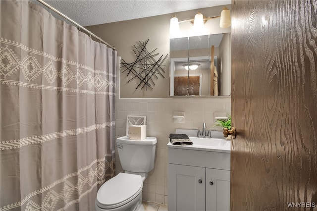 bathroom featuring vanity, tile walls, toilet, and a textured ceiling