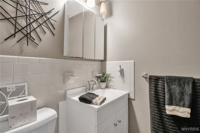 bathroom featuring vanity, tile walls, and toilet