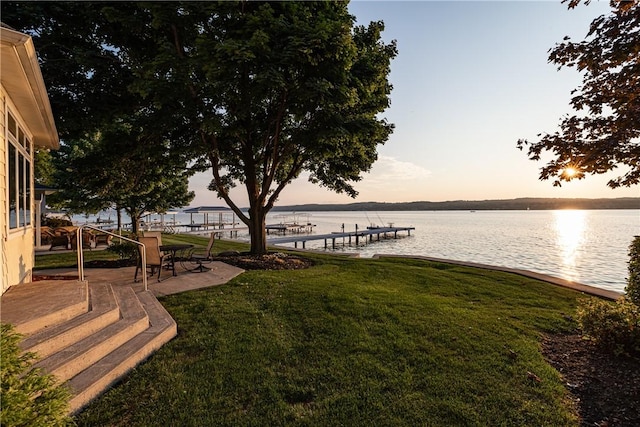 dock area with a water view, a lawn, and a patio area