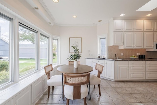 dining area with light tile patterned floors, a skylight, ornamental molding, and recessed lighting