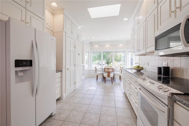 kitchen featuring recessed lighting, white appliances, a skylight, light tile patterned floors, and decorative backsplash