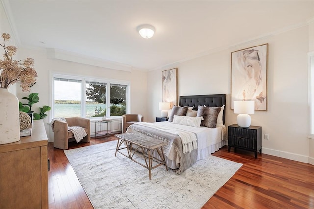 bedroom featuring baseboards, wood finished floors, and ornamental molding