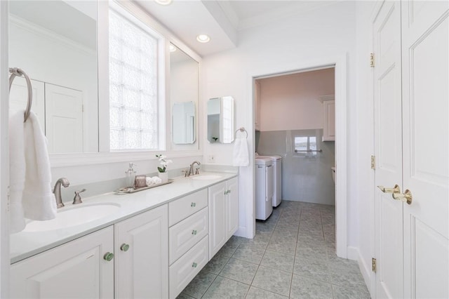 full bath with tile patterned flooring, ornamental molding, washing machine and dryer, and a sink