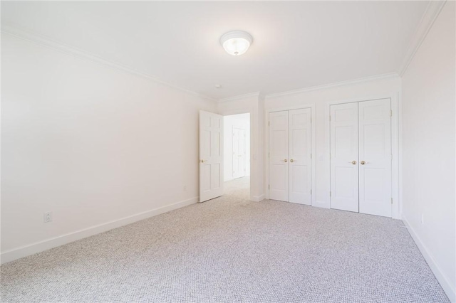 unfurnished bedroom featuring baseboards, multiple closets, carpet floors, and ornamental molding