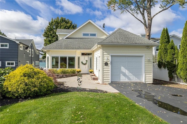 view of front of home featuring a garage, driveway, roof with shingles, and a front yard