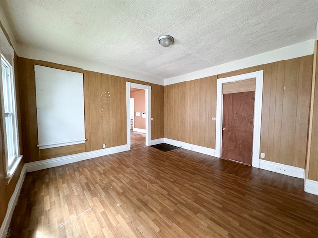 spare room with wooden walls, hardwood / wood-style floors, and a textured ceiling