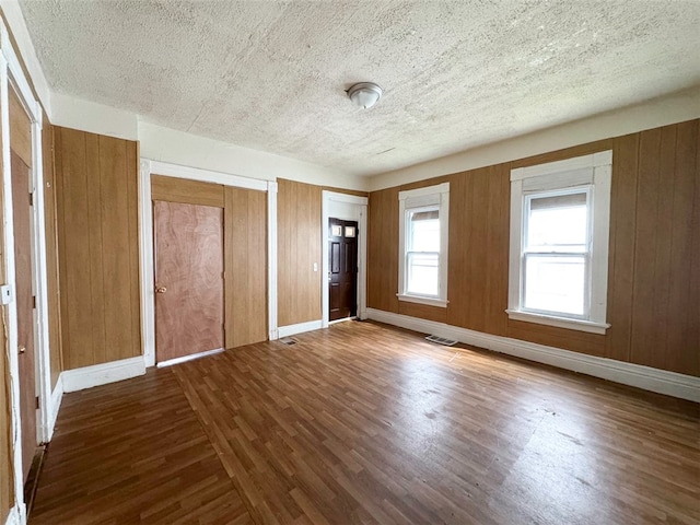 unfurnished bedroom featuring hardwood / wood-style flooring, wood walls, and a textured ceiling