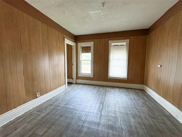 unfurnished room featuring wood walls, wood-type flooring, and a textured ceiling