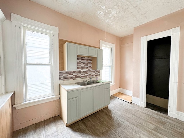 kitchen featuring a textured ceiling, light hardwood / wood-style flooring, backsplash, and sink