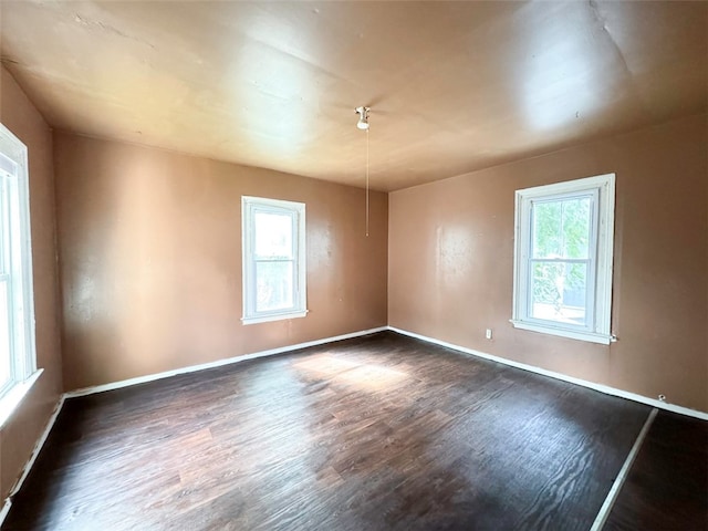 empty room featuring a healthy amount of sunlight and dark hardwood / wood-style floors