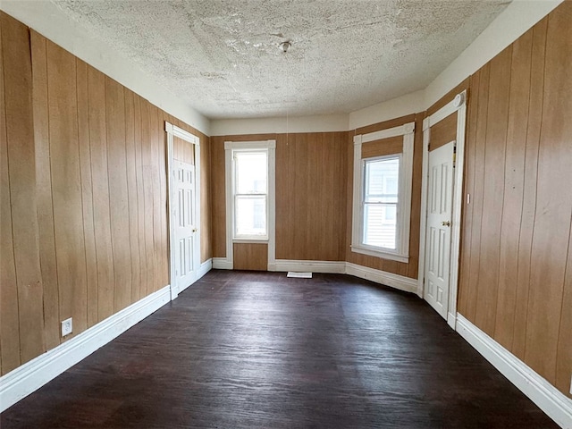 foyer entrance with a textured ceiling, dark hardwood / wood-style floors, and wood walls