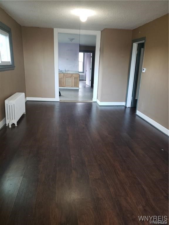 unfurnished room with radiator, a textured ceiling, and dark wood-type flooring