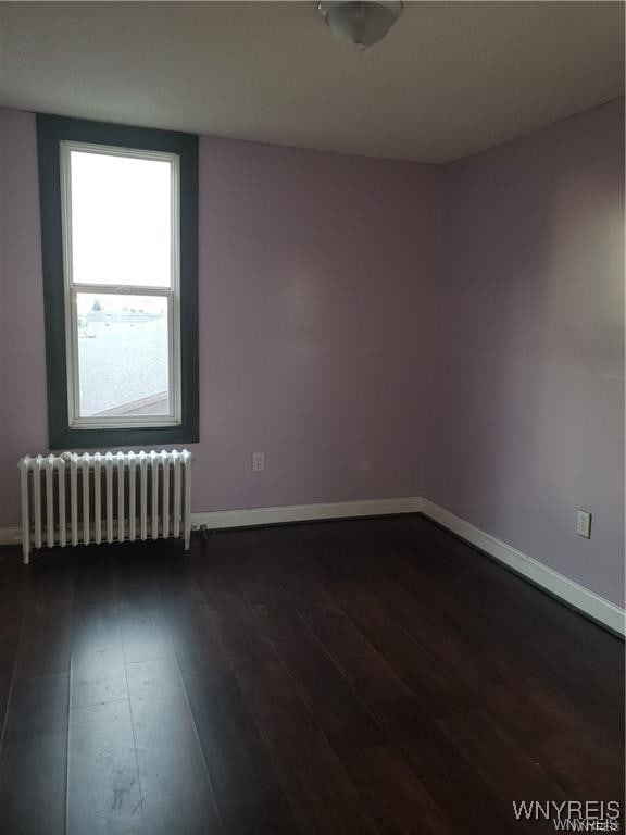 spare room featuring dark hardwood / wood-style floors and radiator