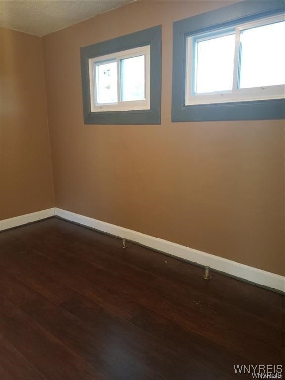 unfurnished room with plenty of natural light, dark hardwood / wood-style flooring, and a textured ceiling