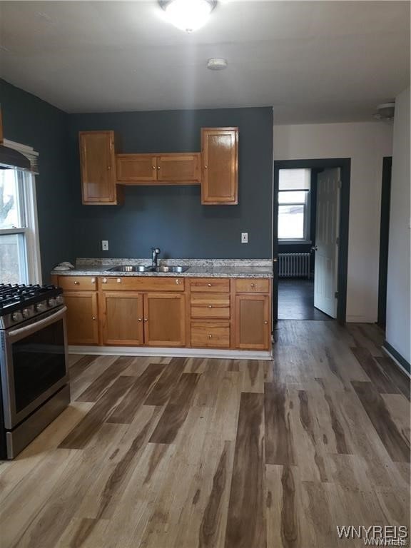 kitchen featuring stainless steel range with gas stovetop, a wealth of natural light, radiator, and wood-type flooring