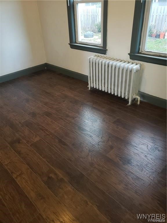 unfurnished room with radiator and dark wood-type flooring